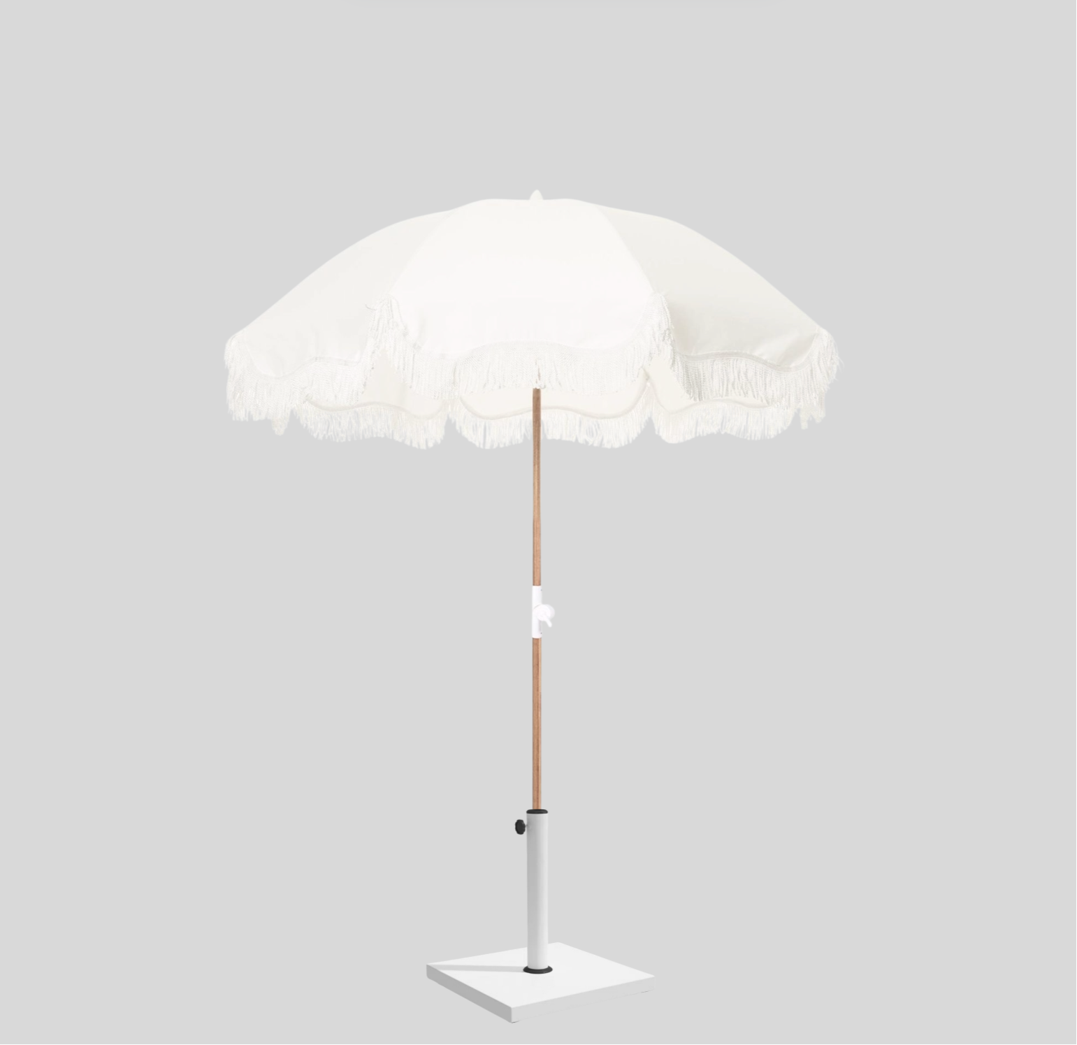 White round umbrella with fringe trim and wooden pole, ideal for beach weddings or summer events.
