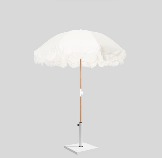 White round umbrella with fringe trim and wooden pole, ideal for beach weddings or summer events.